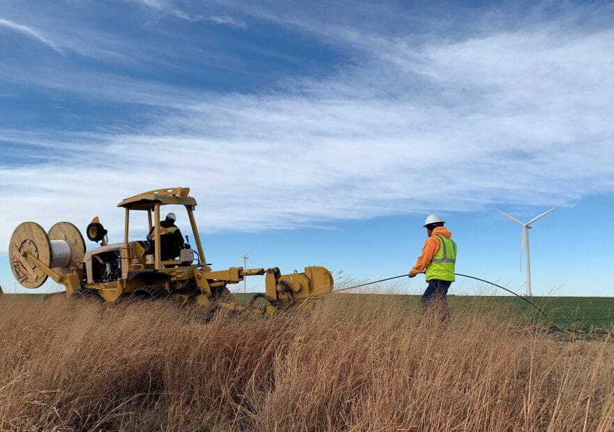A man installing fiber next to a field