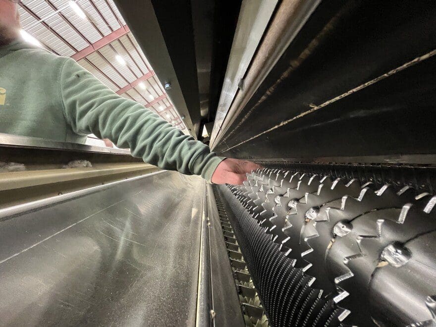 A man pointing to a piece of cotton gin machinery