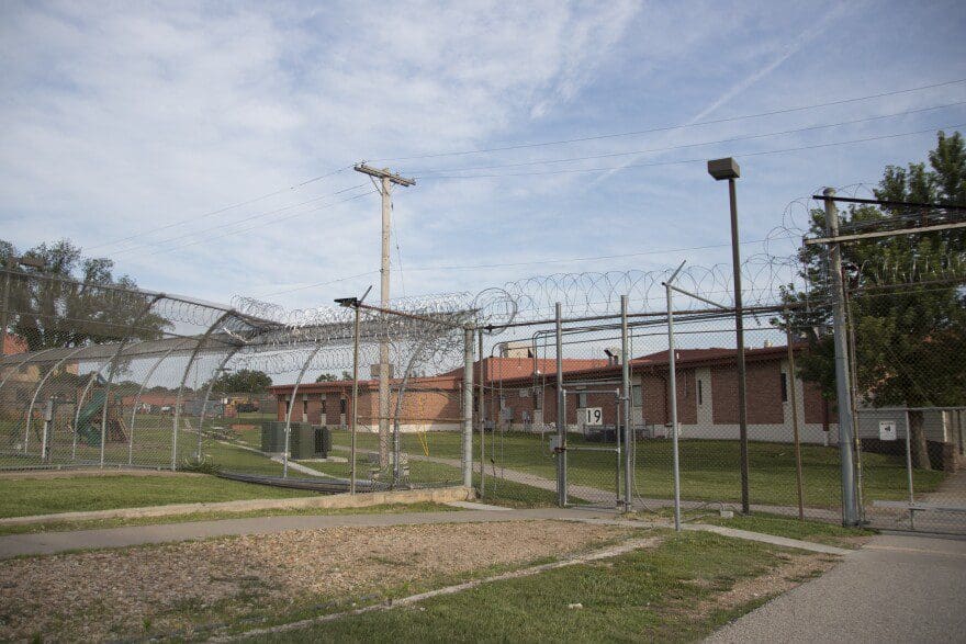 A photo of the prison yard surrounded by fences topped with barbed wire. 