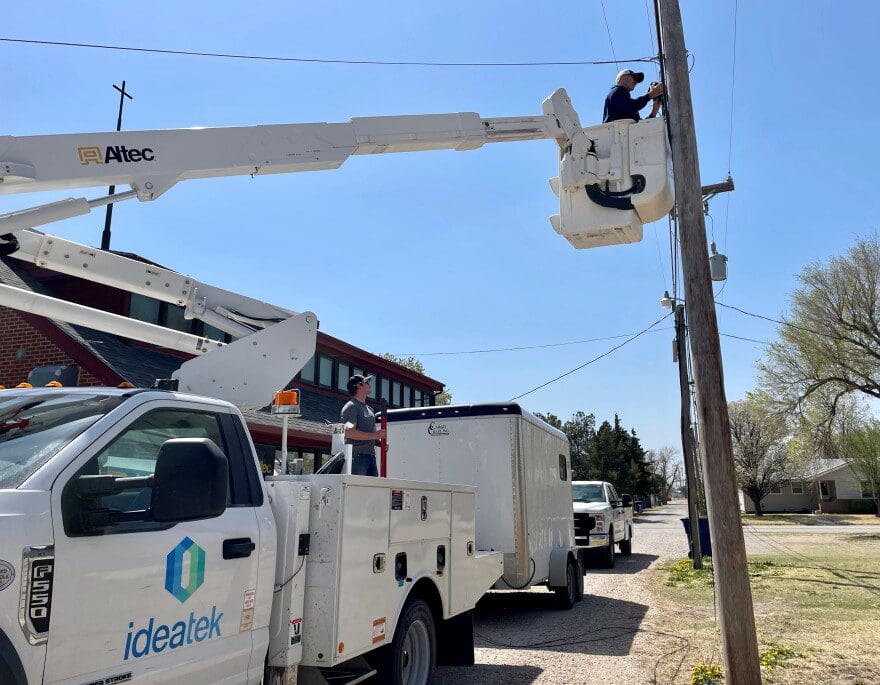 A man in a cherry picker lift wires a pole with fiber